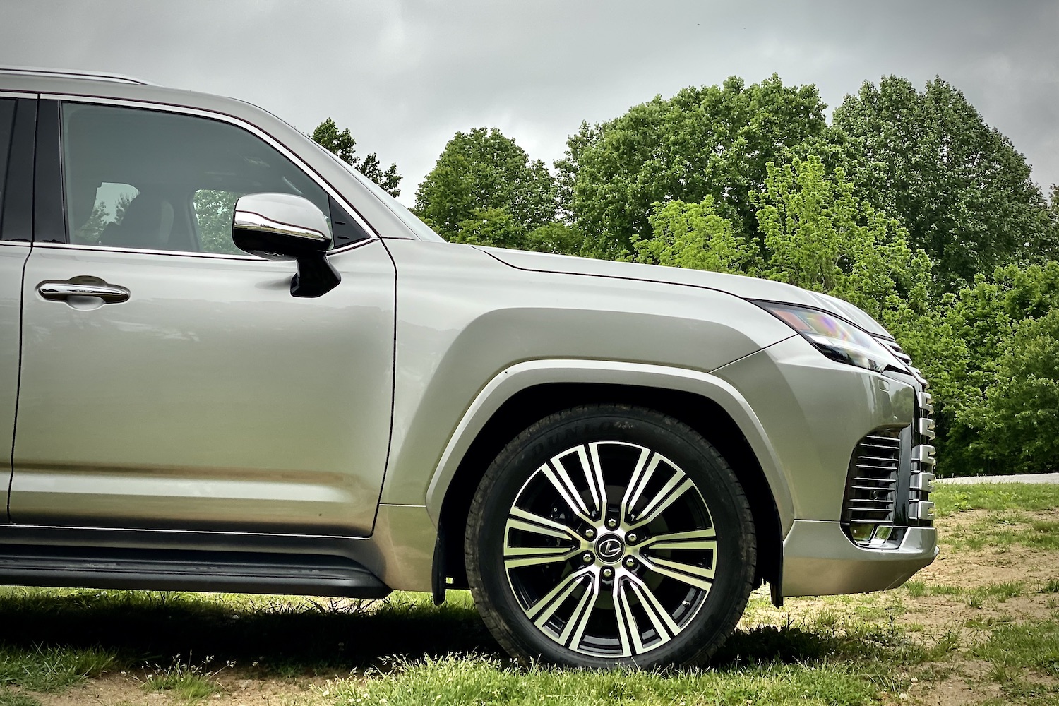 Side profile view of the 2022 Lexus LX 600 front end from the passenger's side in a grassy field.