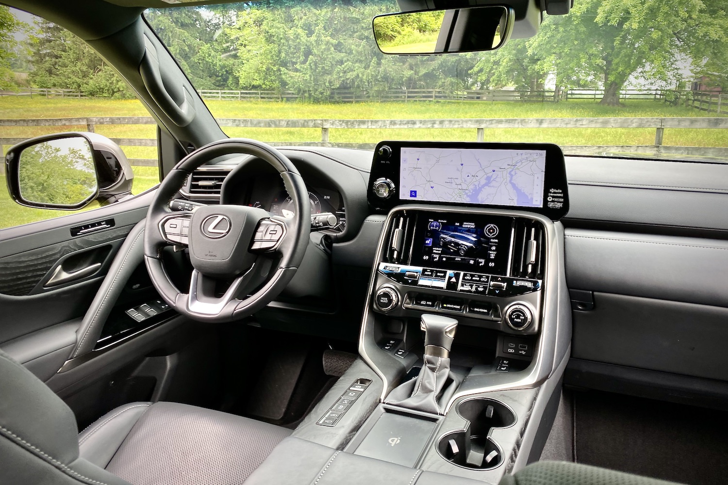 Close up of 2022 Lexus LX 600 dashboard with trees and grassy field in the back.