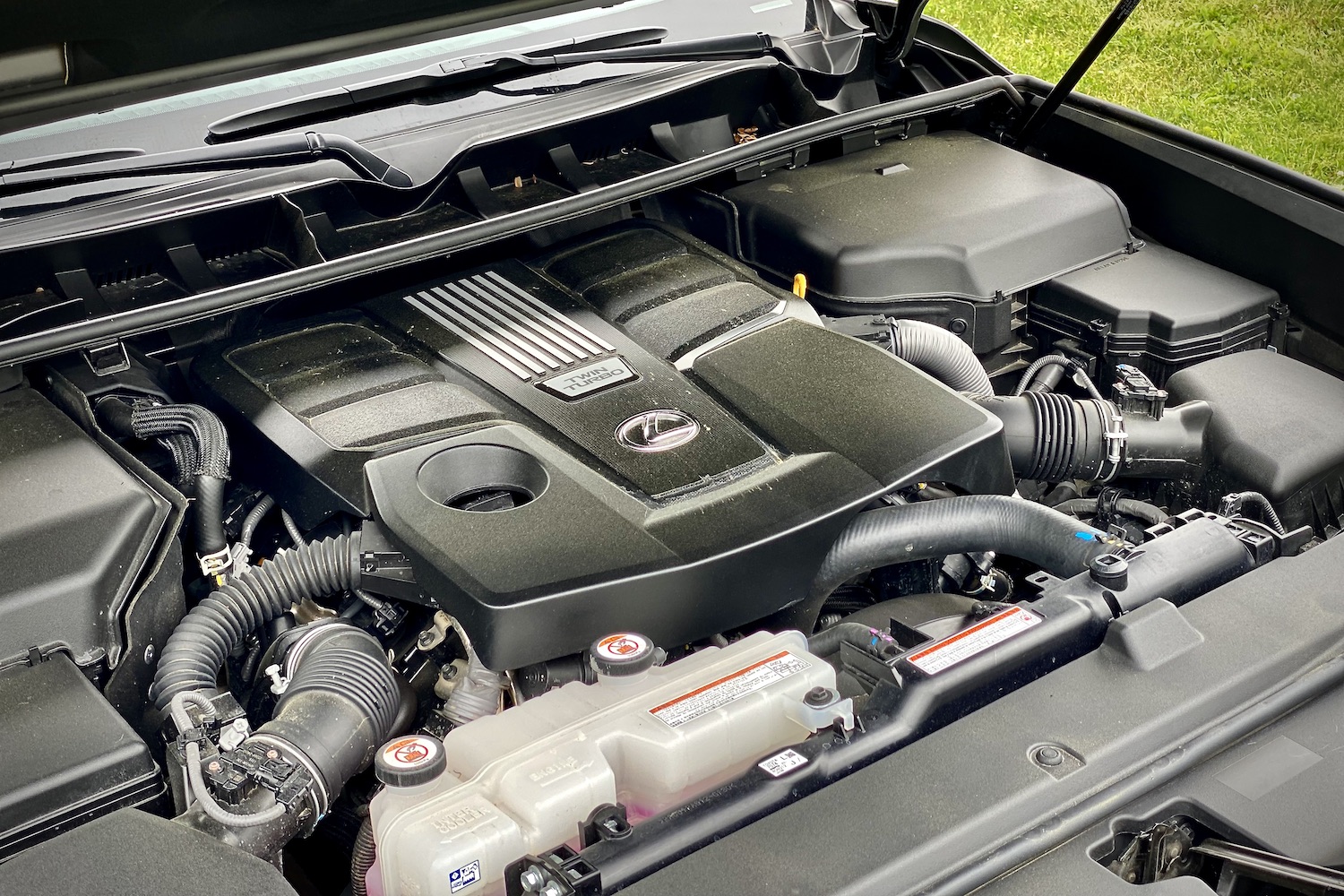 Close up of engine bay in the 2022 Lexus LX 600 with grass in the back.