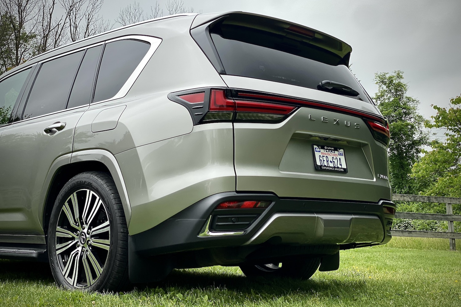 Close up of 2022 Lexus LX 600 rear end angle from driver's side on a grassy field.