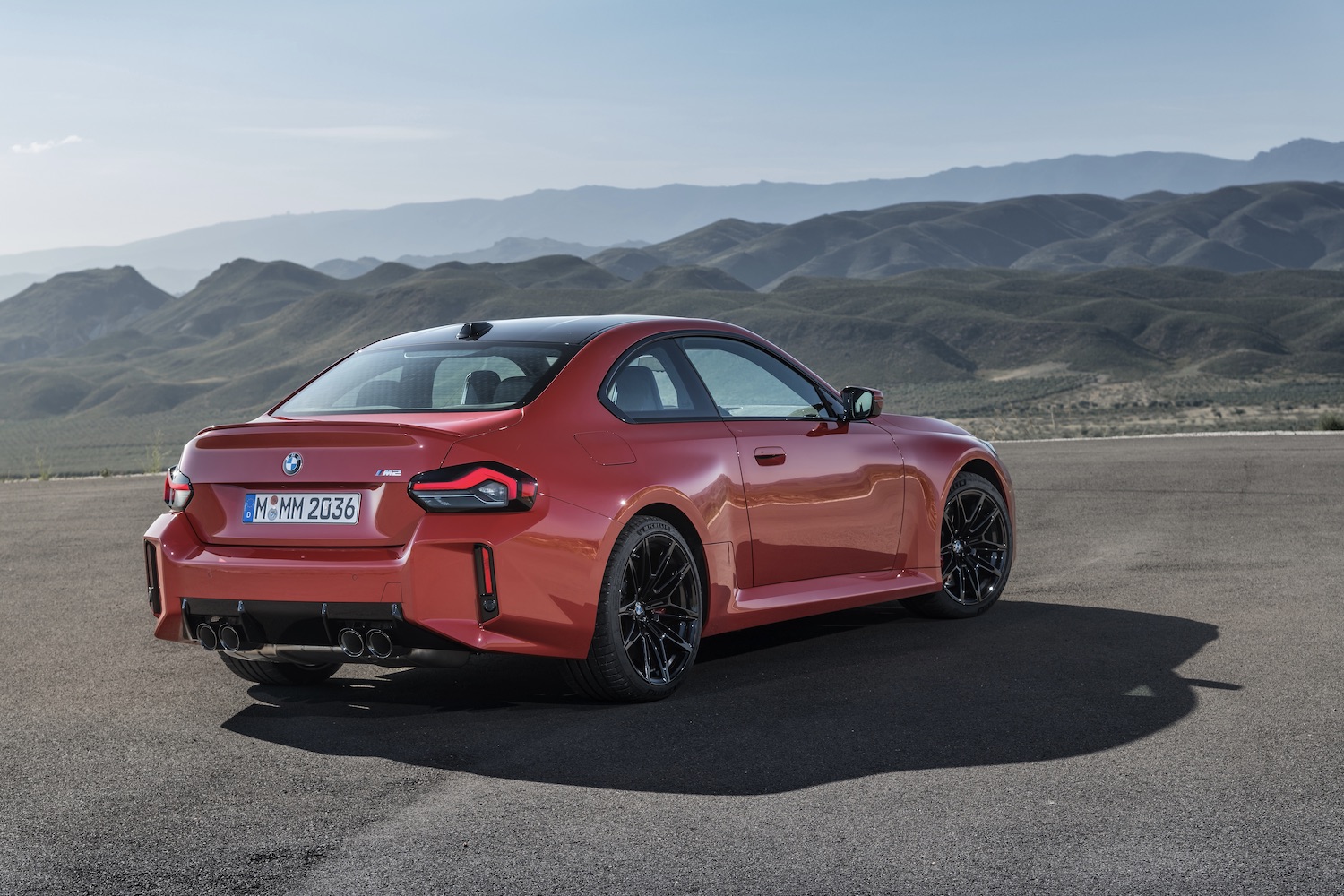 2023 BMW M2 rear end angle from the passenger's side with mountains in the back.