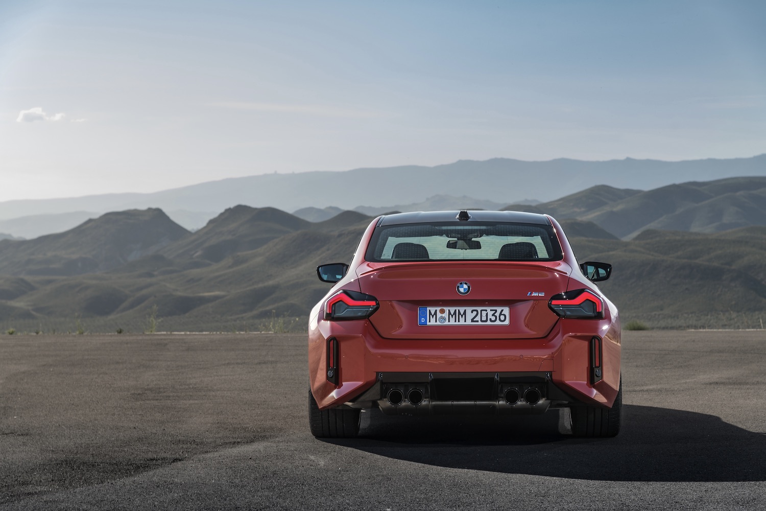 Rear end of 2023 BMW M2 with mountains and blue skies in the back.