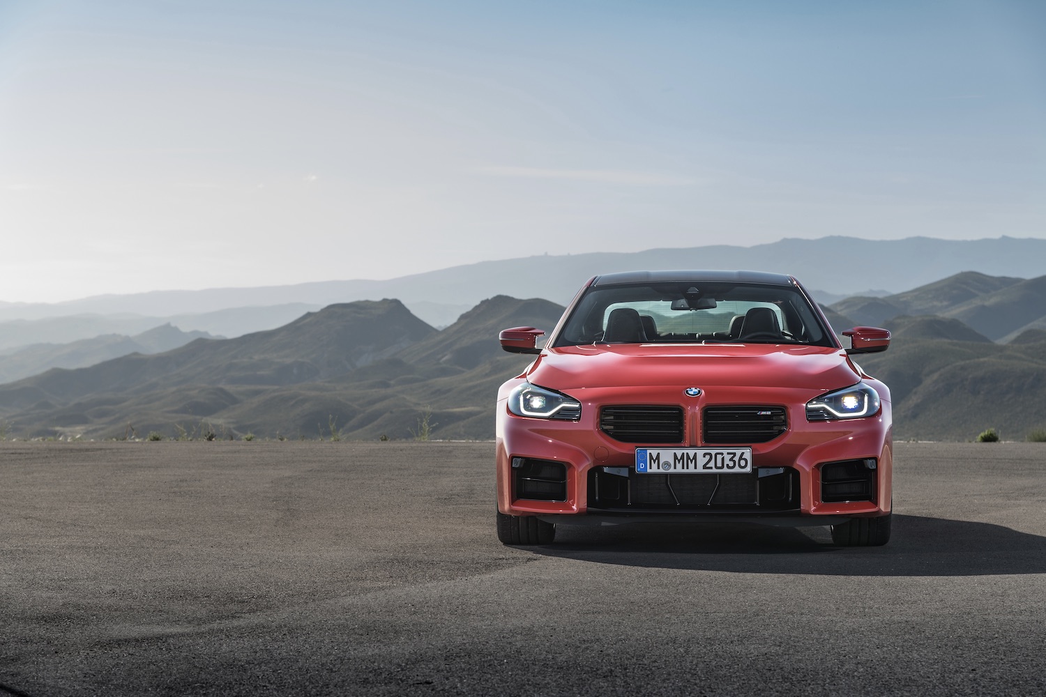 Front end of the 2023 BMW M2 with mountains in the back.