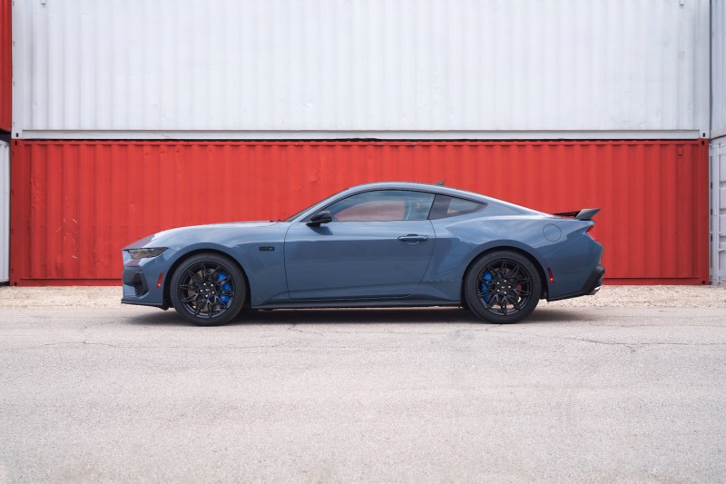 Side profile of 2024 Ford Mustang in front of a metal shipping container.