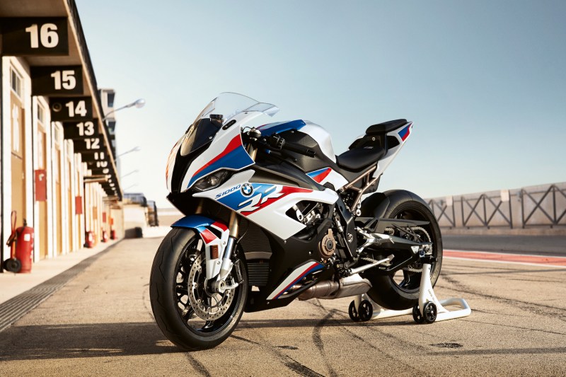 BMW S 1000 RR parked in the pit lane of a race track with blue skies in the back.