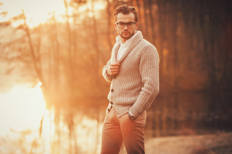 Trendy handsome man posing in autumn park alone