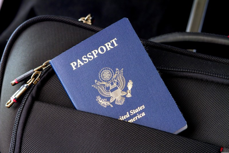 Passport sticking out of a suitcase pocket.