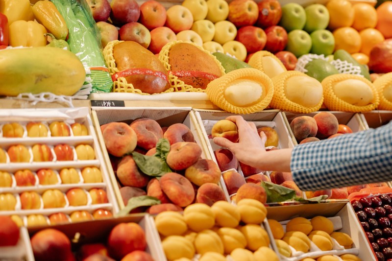 person choosing a peach from the produce section