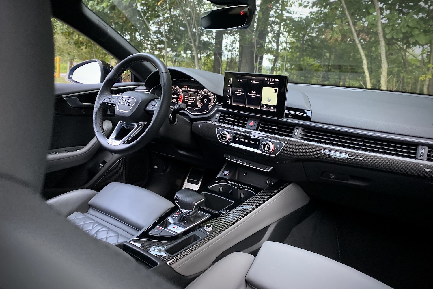 Close up of dashboard in 2023 Audi S5 Sportback with trees in the back.