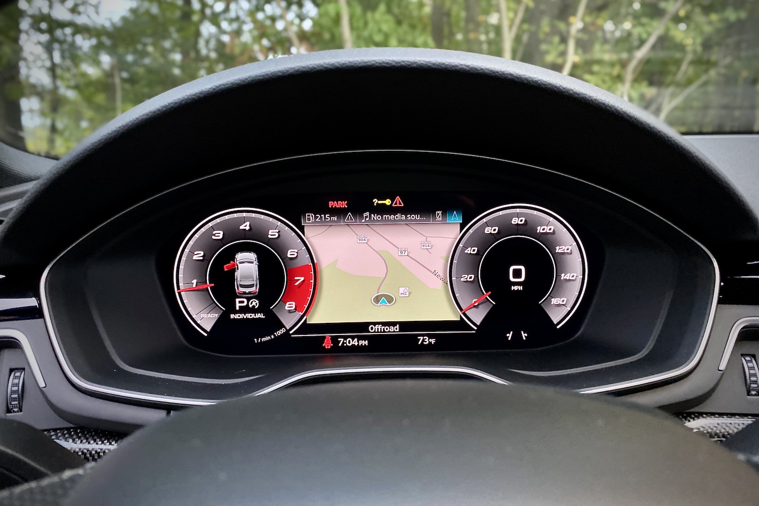 Close up of 2023 Audi S5 Sportback digital instrument cluster with trees in the back.