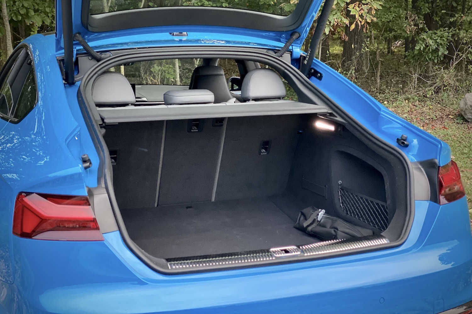 Close up of cargo space in the 2023 Audi S5 Sportback with trees in the back.