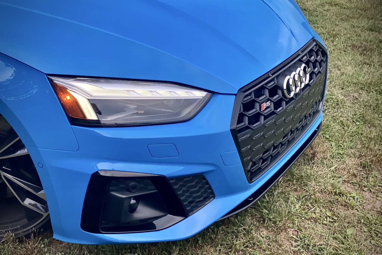 Close up of front end of 2023 Audi S5 Sportback in a grassy field.