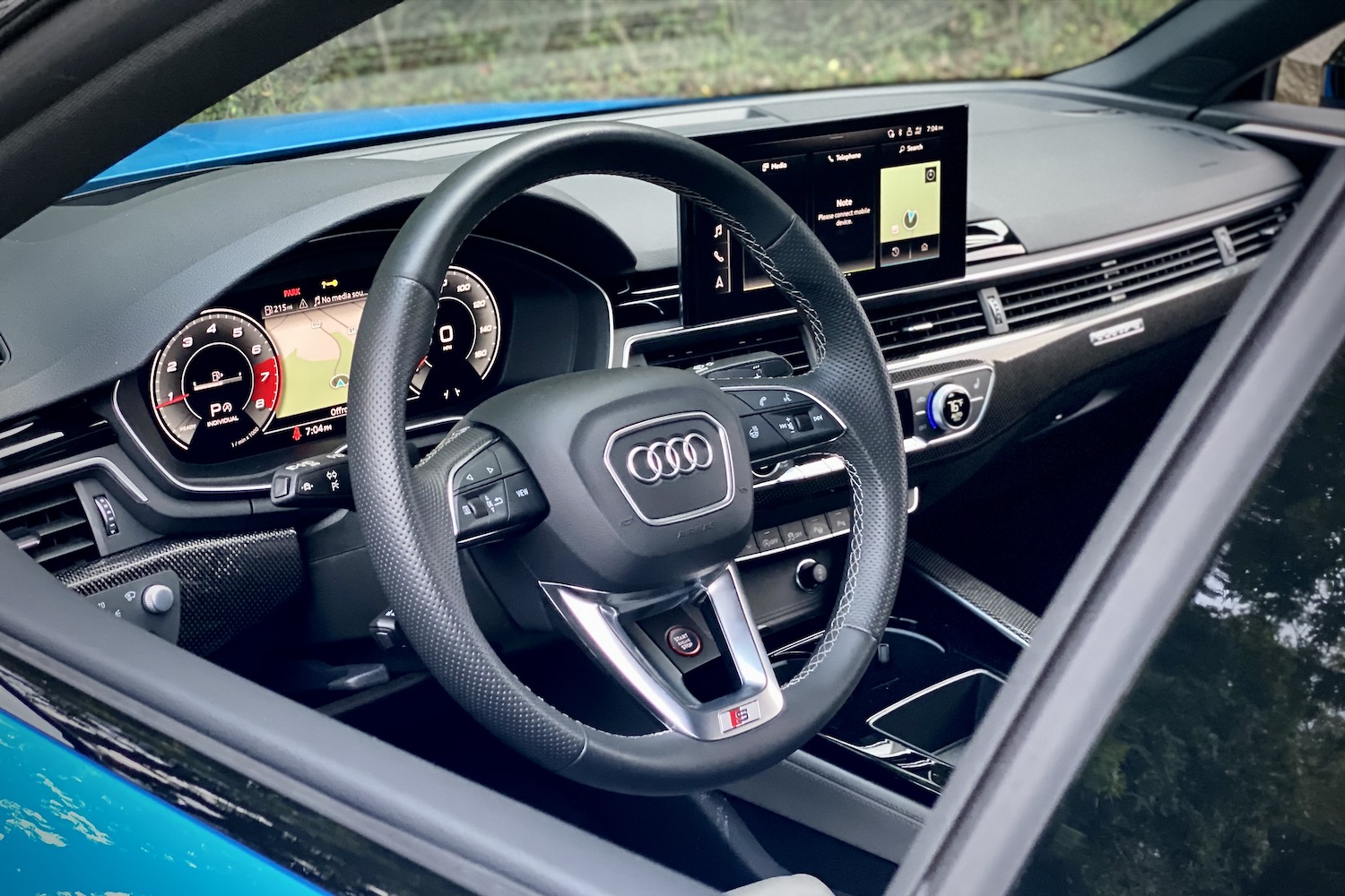 Close up of steering wheel in the 2023 Audi S5 Sportback with trees in the back.