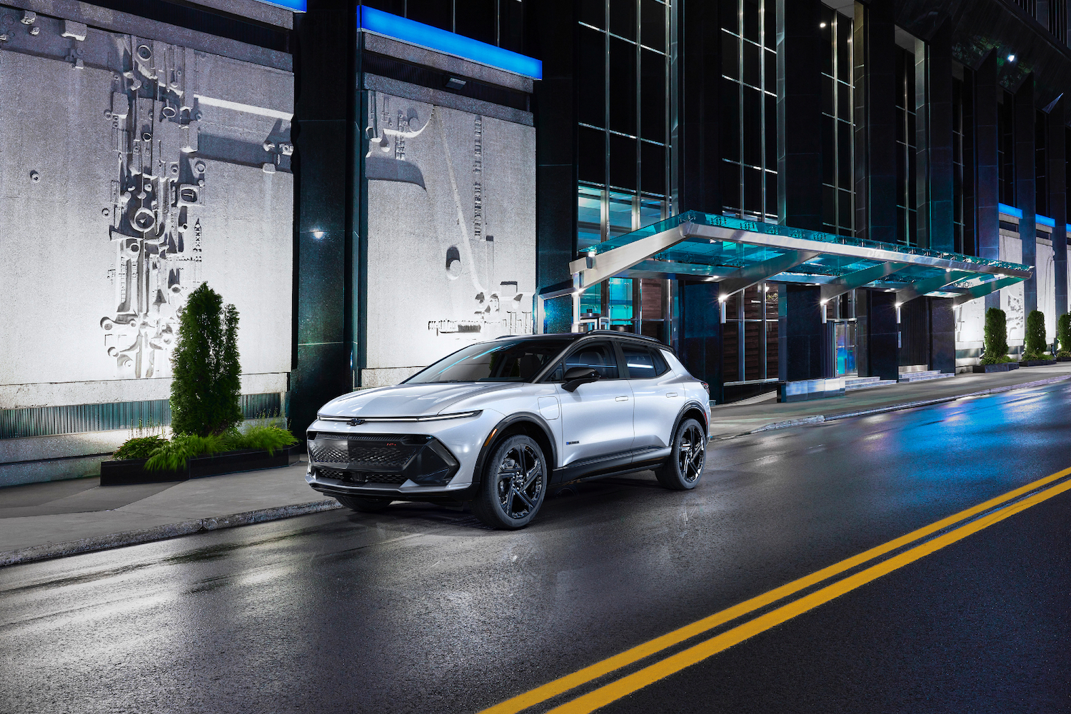 Front end angle of 2024 Chevrolet Equinox 3RS from the driver's side in front of a building at night on a wet street.