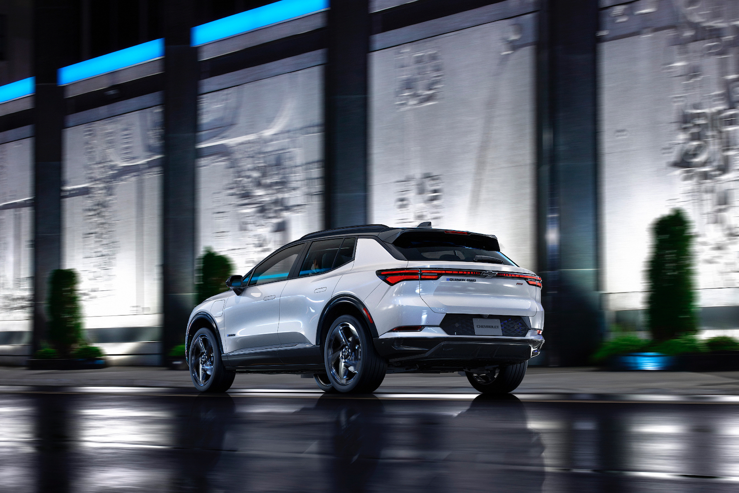 Rear end angle of 2024 Chevrolet Equinox 3RS from driver's side in front of a building at night.