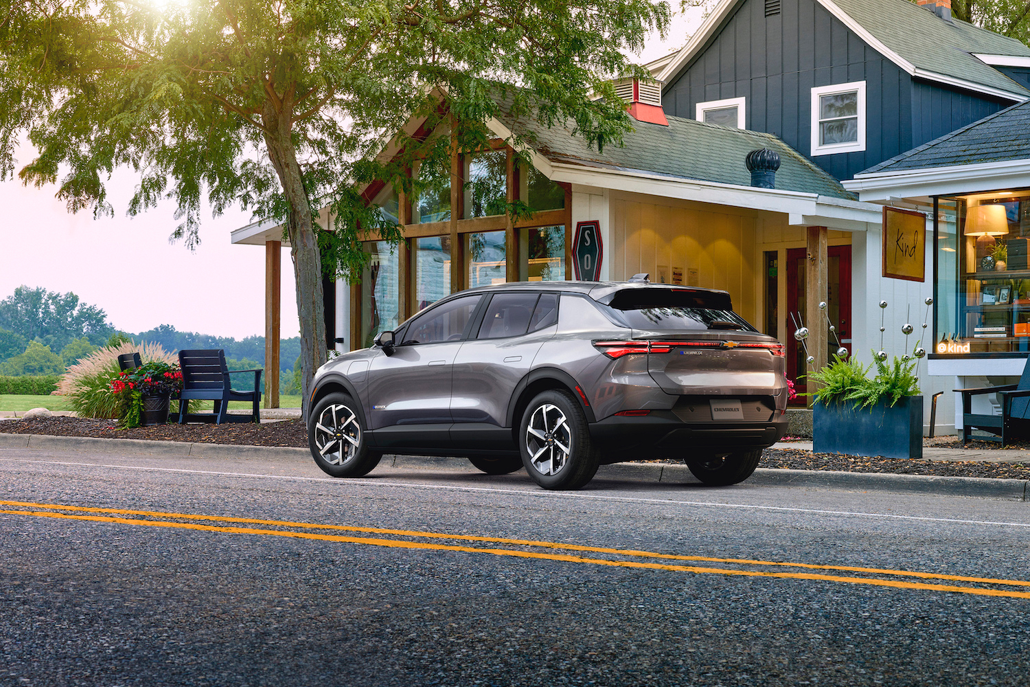 2024 Chevrolet Equinox EV 1LT rear angle from the driver's side in front of a gray building during sunset.