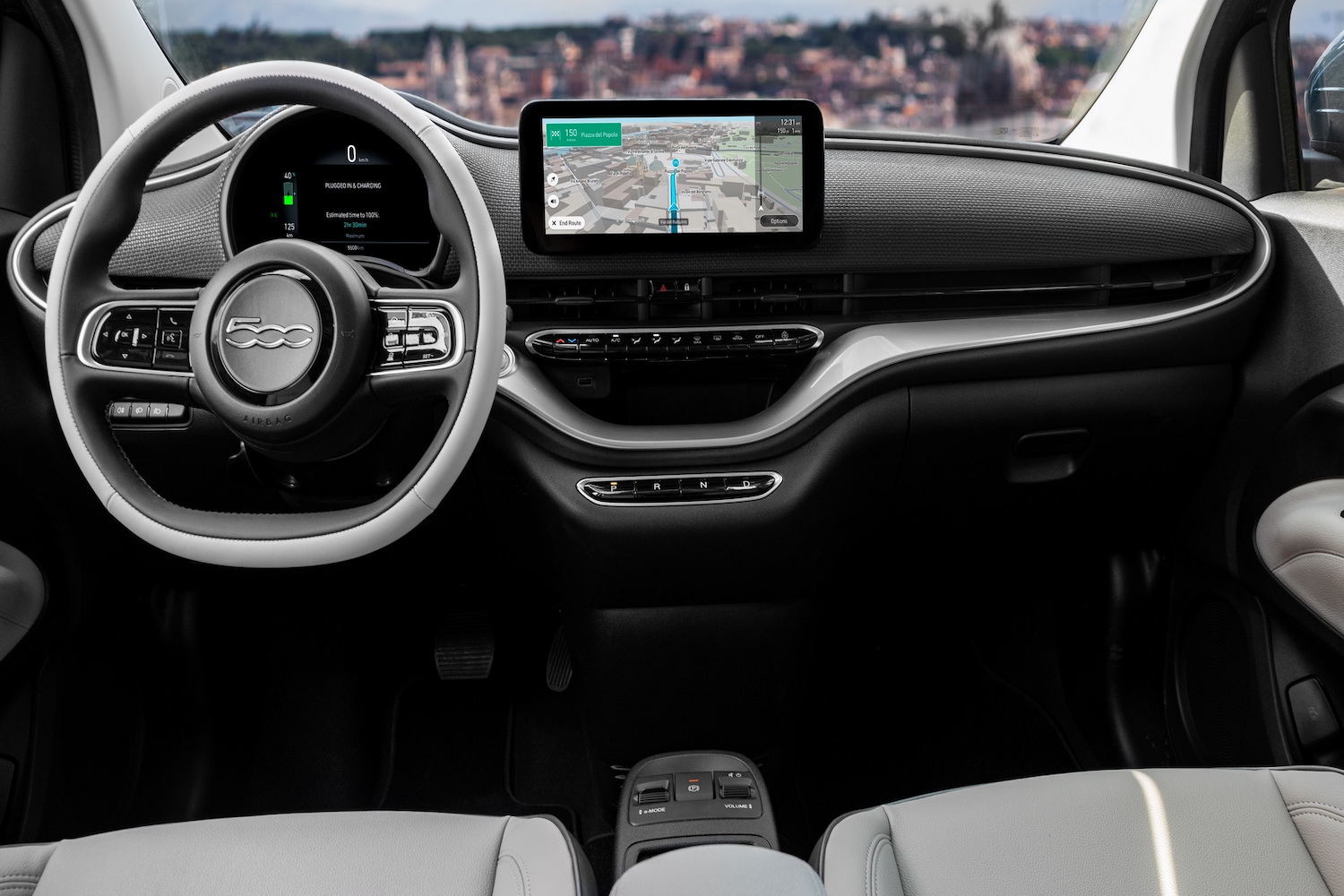 Close up of dashboard in the 2024 Fiat 500e from rear seats with city skyline in the back.