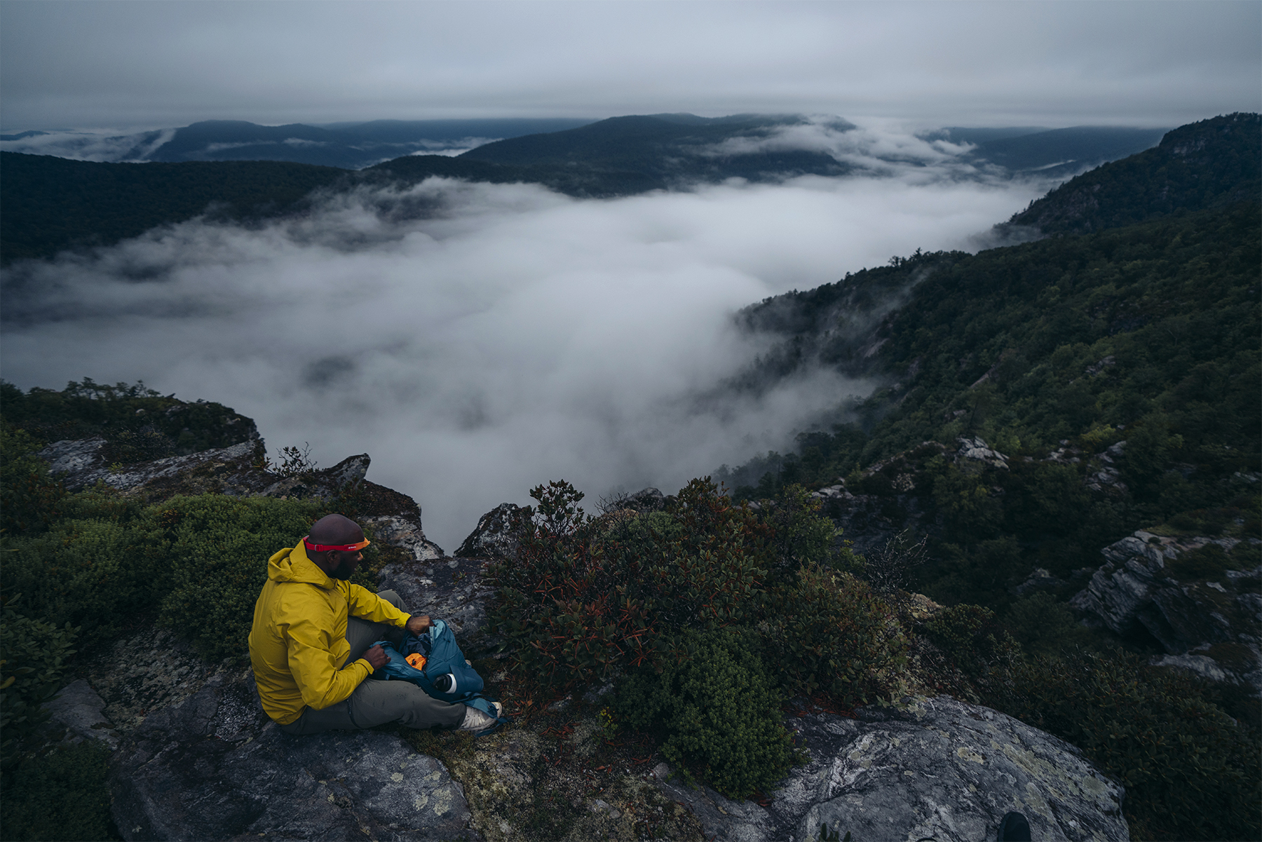 A man sits overlooking a cloud inversion while wearing the BioLite HeadLamp 425