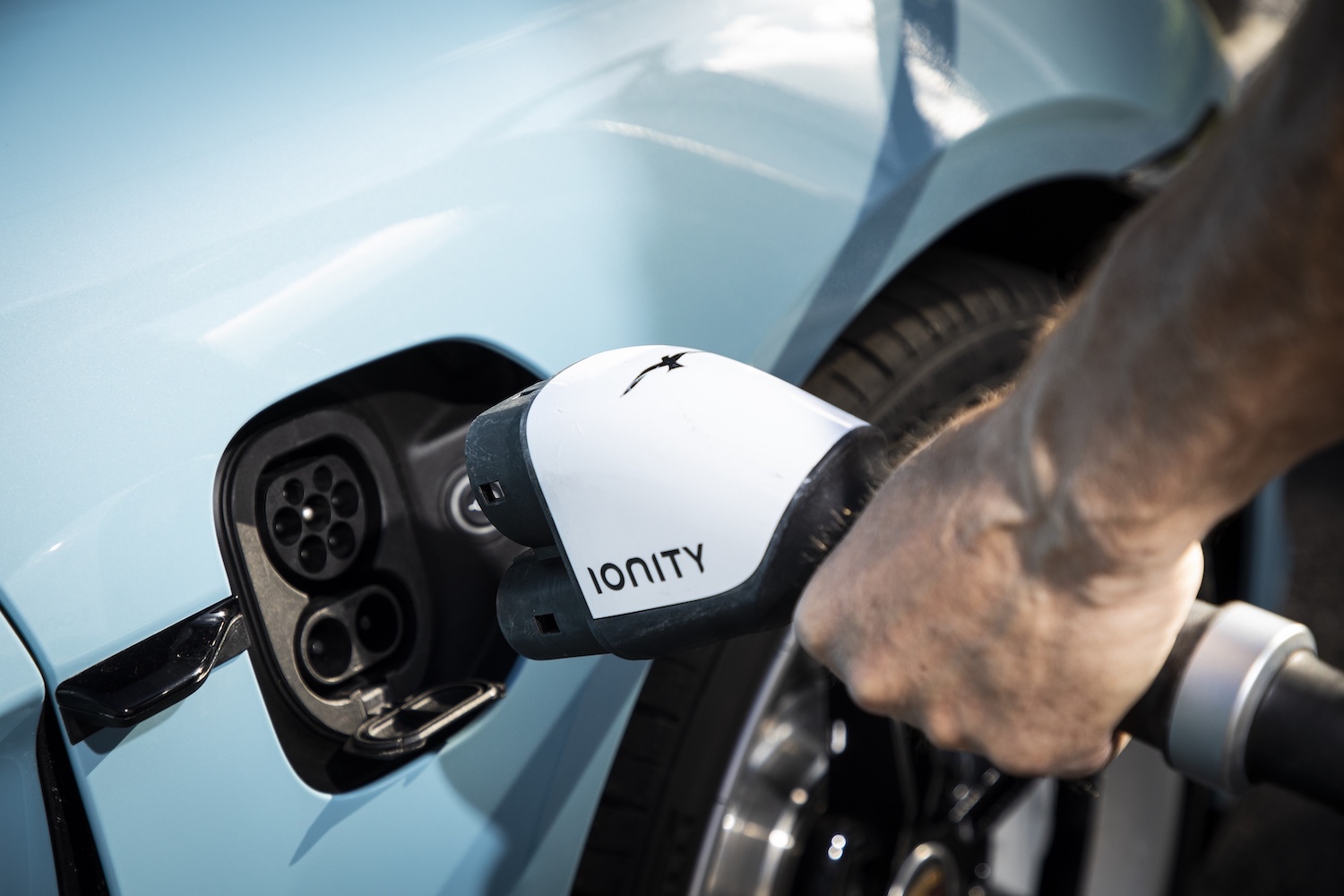 Man connecting a charger to a blue 2022 Porsche Taycan.