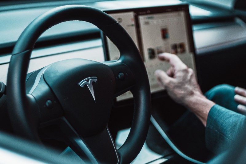 Person using the touchscreen feature while driving a Tesla