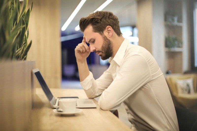 stressed out man looking at laptop while at work