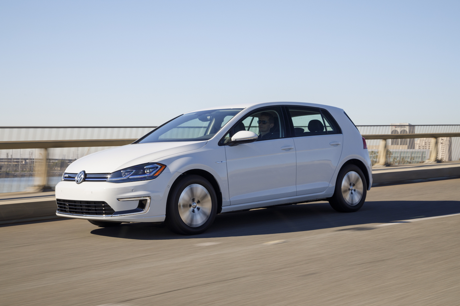 2017 Volkswagen e-Golf driving down the road in front of blue skies.