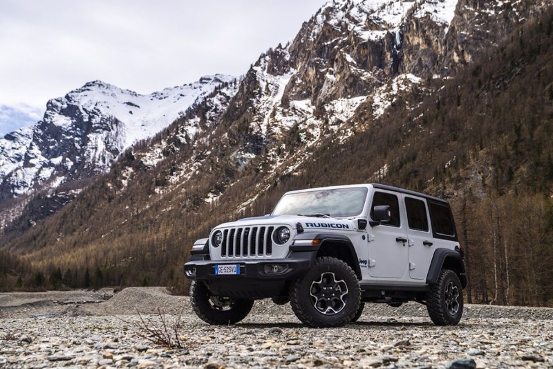 Front end angle of 2021 Jeep Wrangler Rubicon in front of snow-capped mountains on a rocky trail.