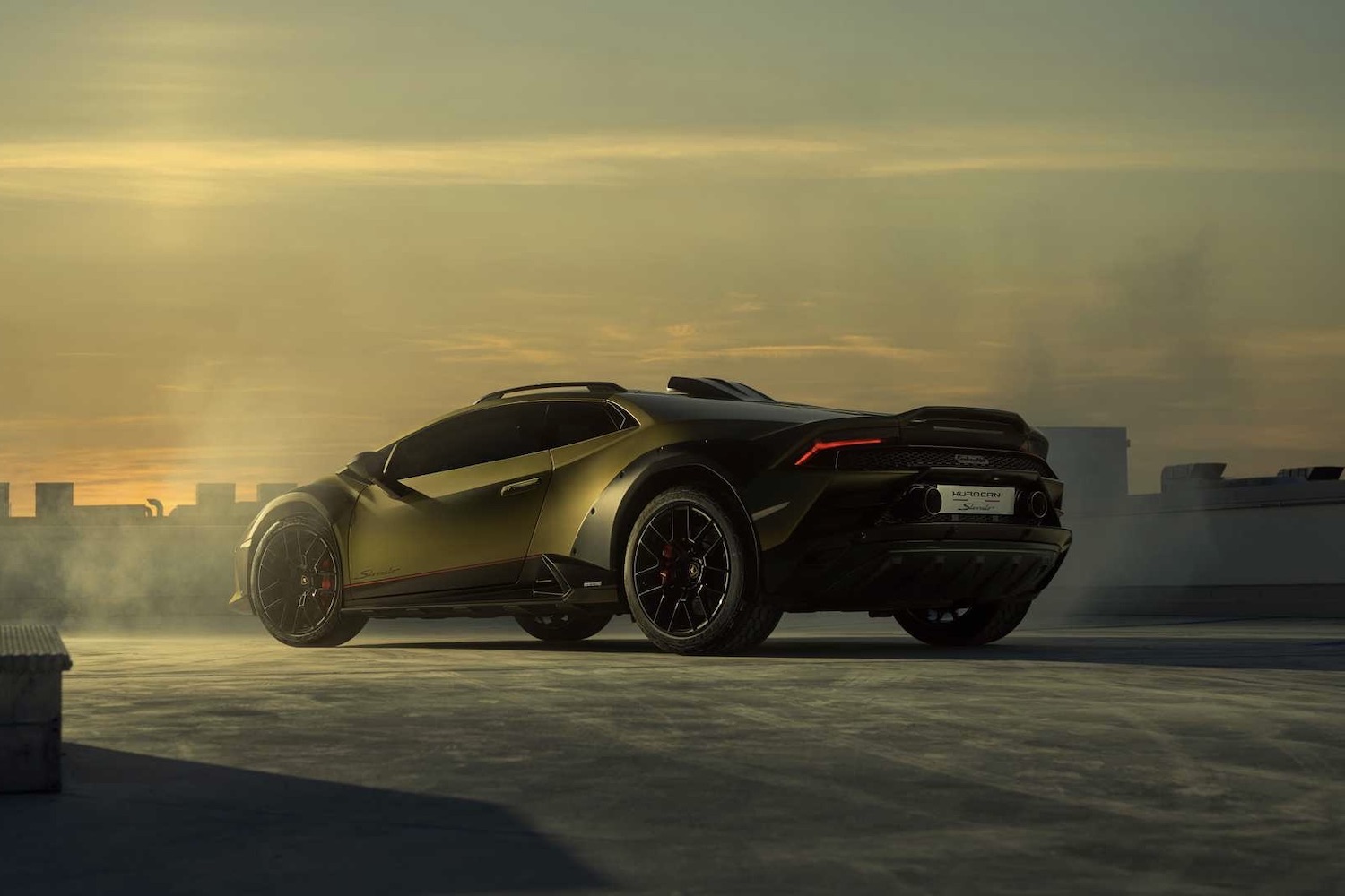 2023 Lamborghini Huracan rear end angle from driver's side in front of city during sunset with smoke in the back.