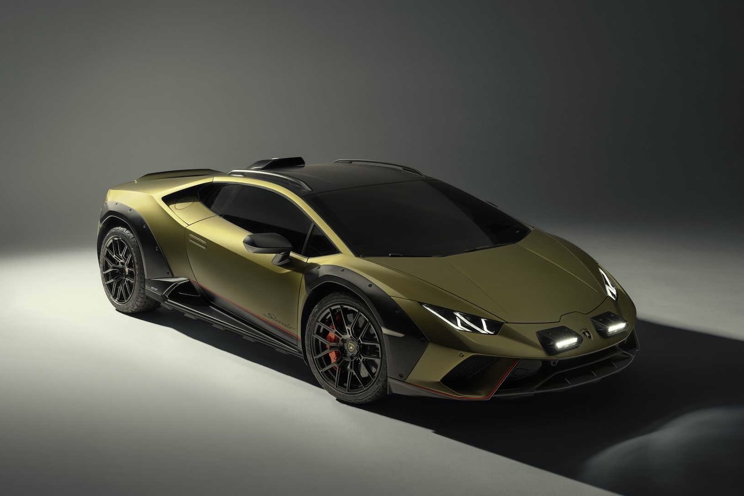 Side profile angle of 2023 Lamborghini Huracan from passenger's side in a studio with dramatic lighting and headlights on.