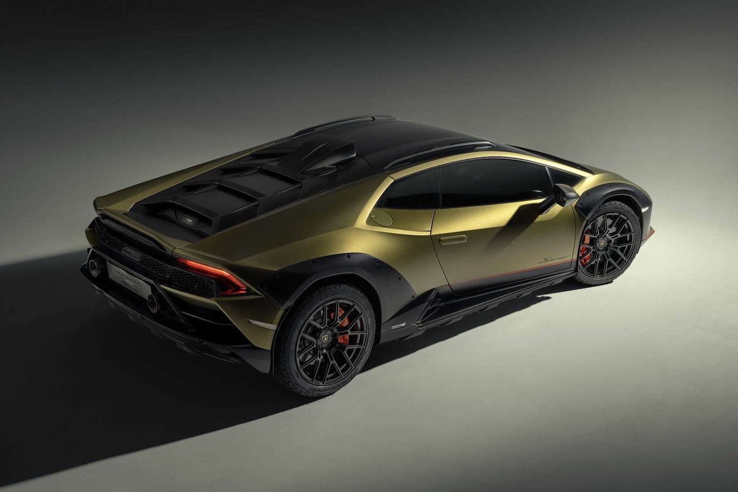 Rear side angle of 2023 Lamborghini Huracan from passenger's side in a studio with dramatic lighting.
