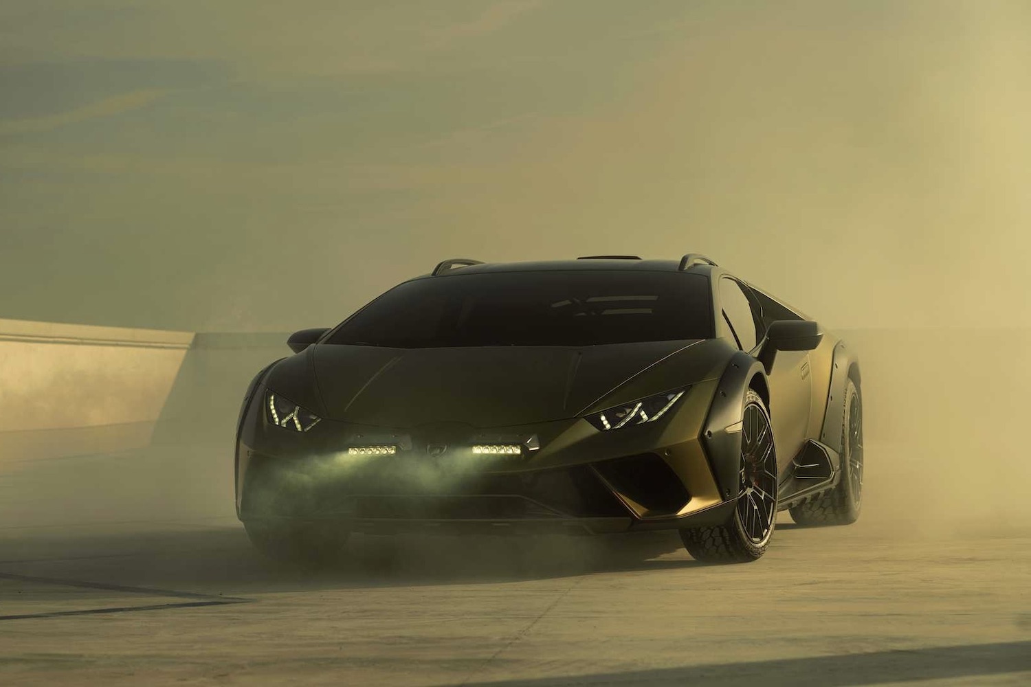 Front end angle of 2023 Lamborghini Huracan from driver's side with smoke in the back during sunset.