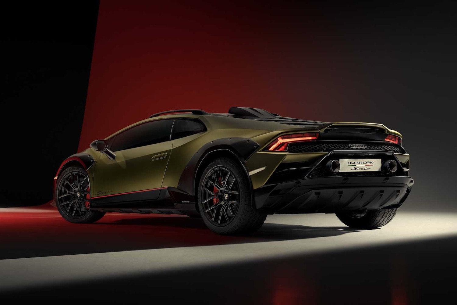 2023 Lamborghini Huracan rear end angle from driver's side in a studio with red, black, and white lighting with taillights on.
