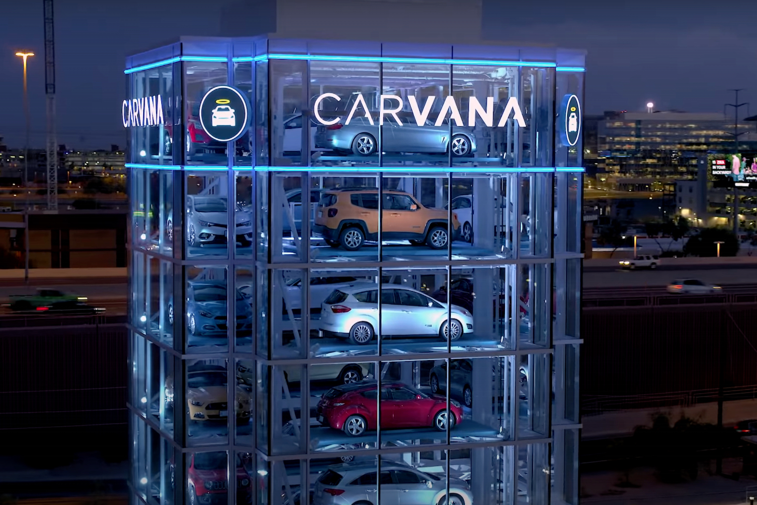 Close up of front end of Carvana Vending Machine at night time in front of buildings.