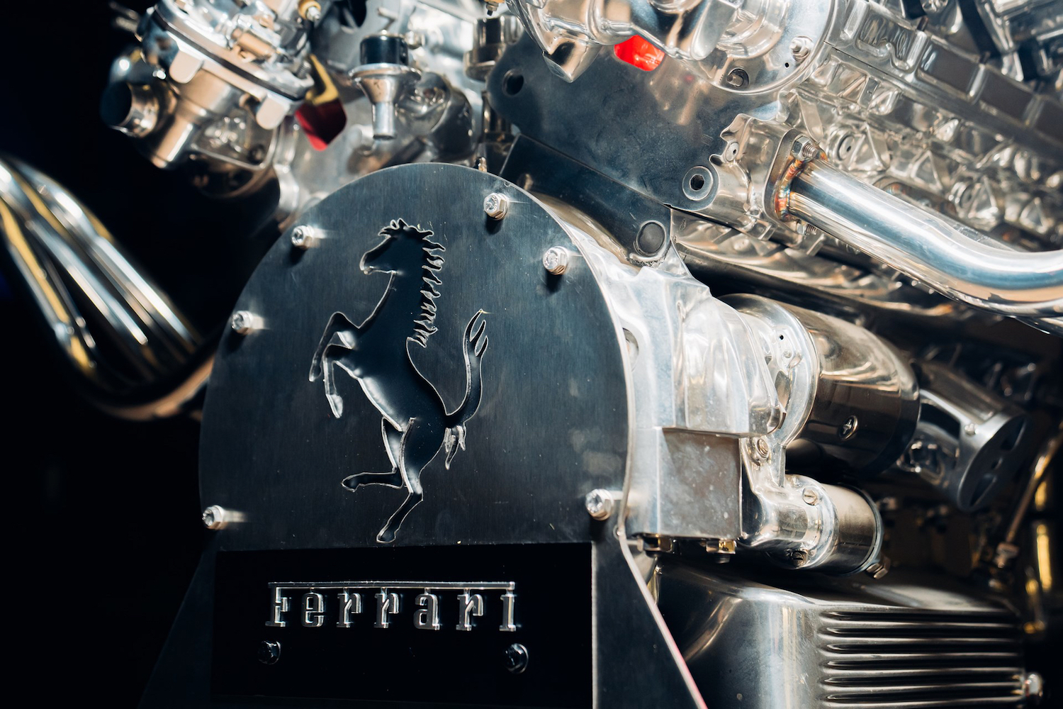 Close up of Ferrari badge on Ferrari V12 Table in front of black screen.