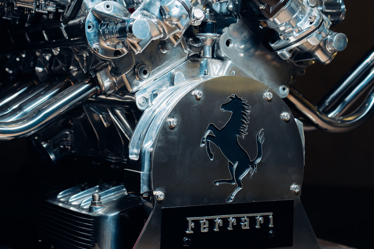 Close up of Ferrari badge on Ferrari V12 Table in front of a black screen.