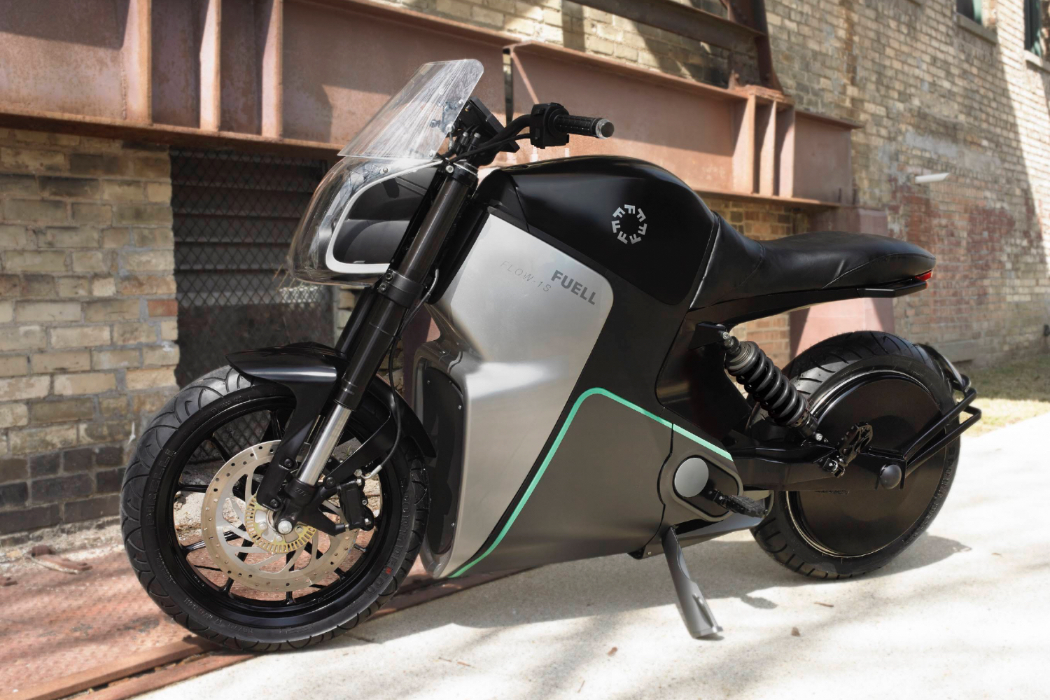 Front end angle of Fuell Fllow parked in an alley in front of a brick building.