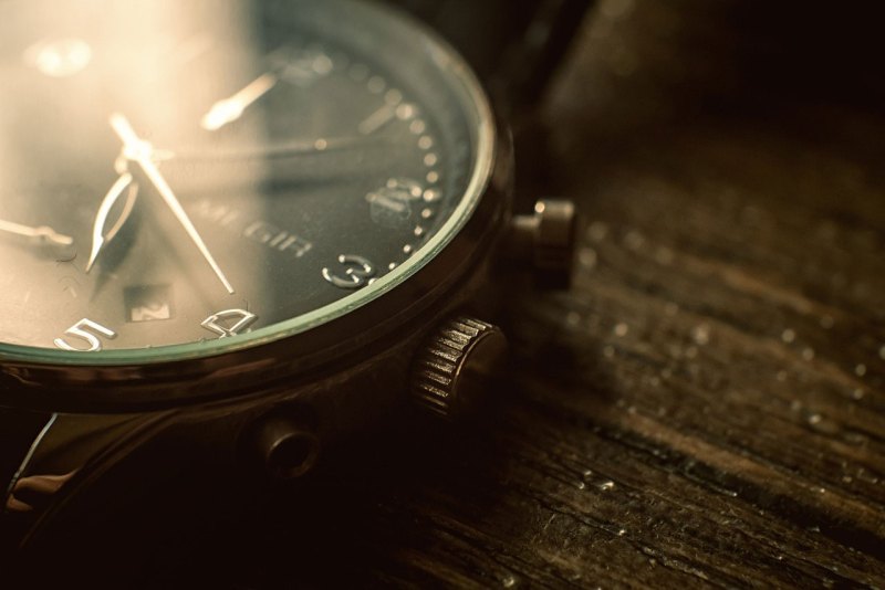 Closeup of metal watch on wood surface.