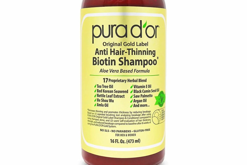 A close-up of a bottle of PURA D'OR Original Gold Label Anti-Thinning Biotin Shampoo.