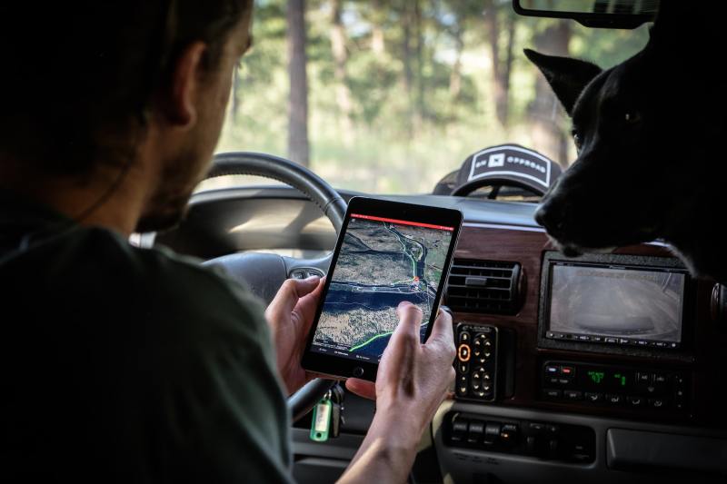 Man sitting in car looking at GPS map on a tablet.
