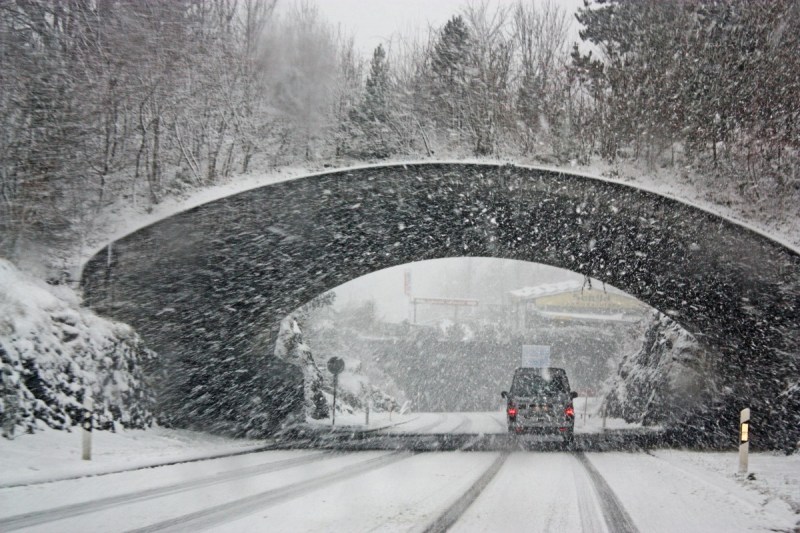 Car driving under bridge during a snow storm