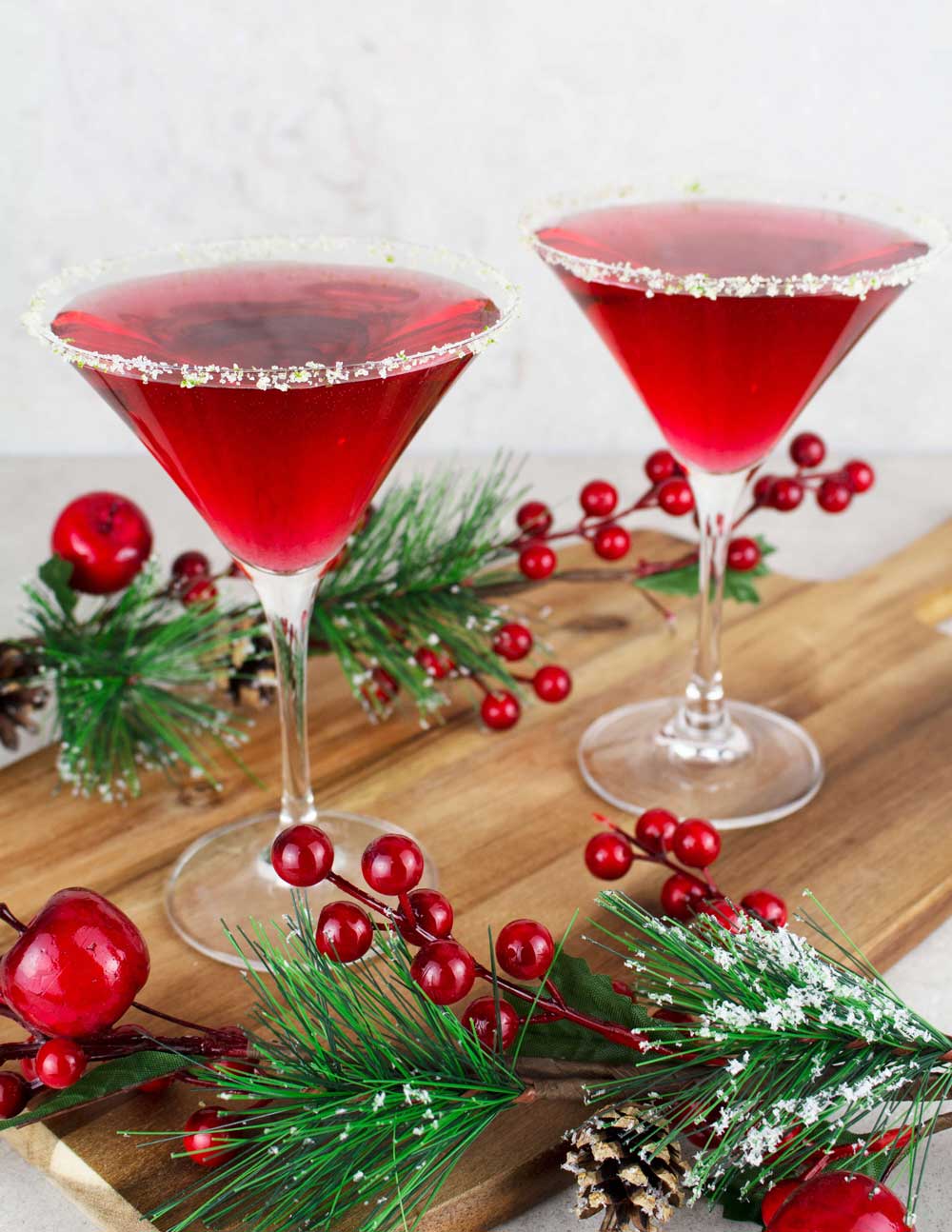 Two glasses of virgin cosmopolitan martinis surrounded by holly sprigs