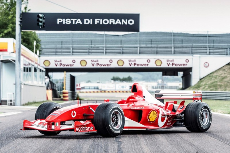 2003 Ferrari F2003 GA race car front end angle parked in the middle of a race track.