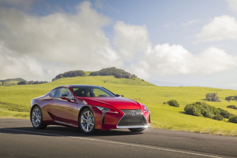 2022 Lexus LC front end angle parked on the side of the road in front of green grassy and hill.