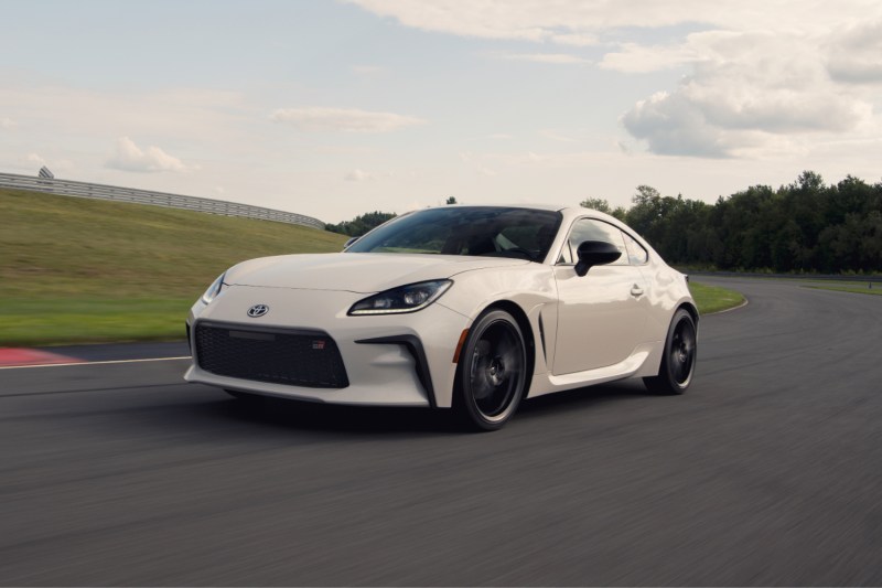 2022 Toyota GR86 Premium front end angle driving on a race track with green trees in the back.