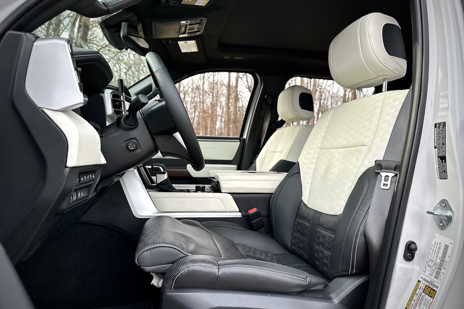 Side profile of front seats in the 2022 Toyota Tundra Hybrid Capstone from outside the vehicle with trees in the background.