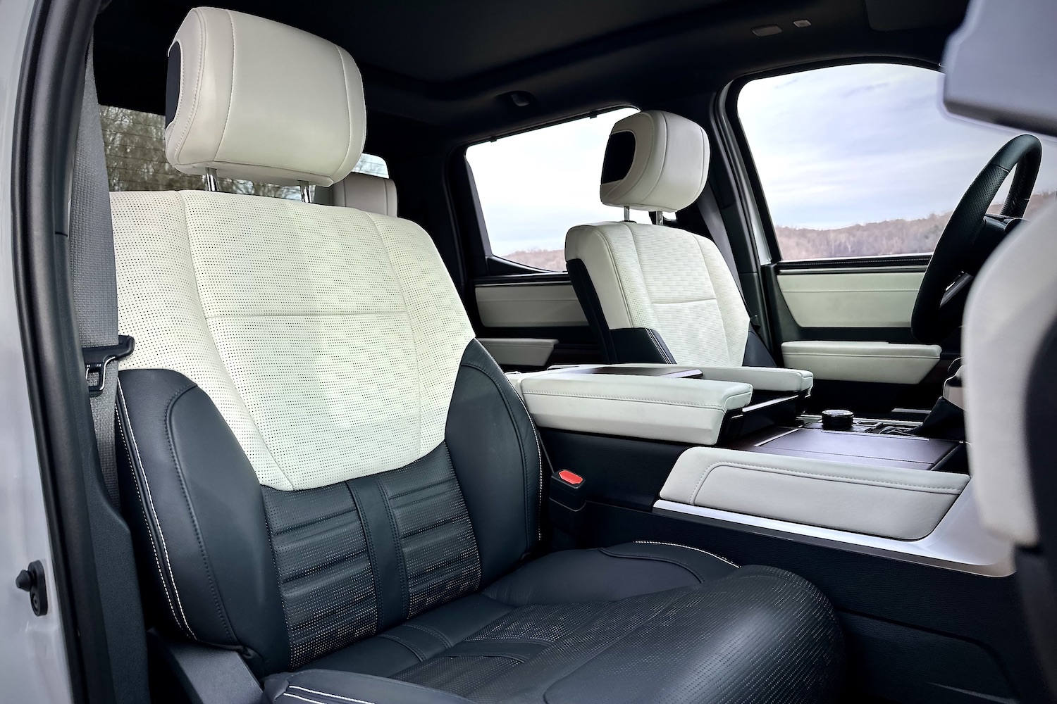 Close up of front seats in the 2022 Toyota Tundra Hybrid Capstone from outside passenger's side with clouds in the background.