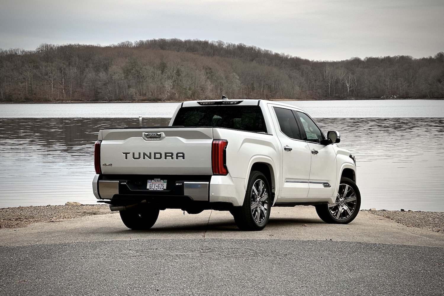 Side rear end angle of 2022 Toyota Tundra Hybrid Capstone parked on a boat ramp in front of a lake.