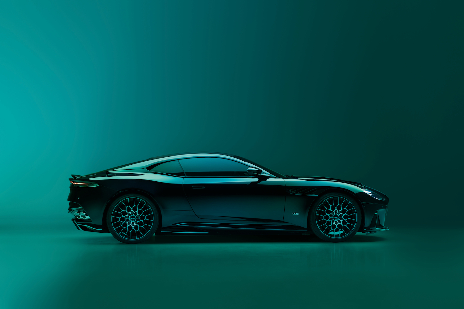 2023 Aston Martin DBS 770 Ultimate side profile in front of a green studio wall.