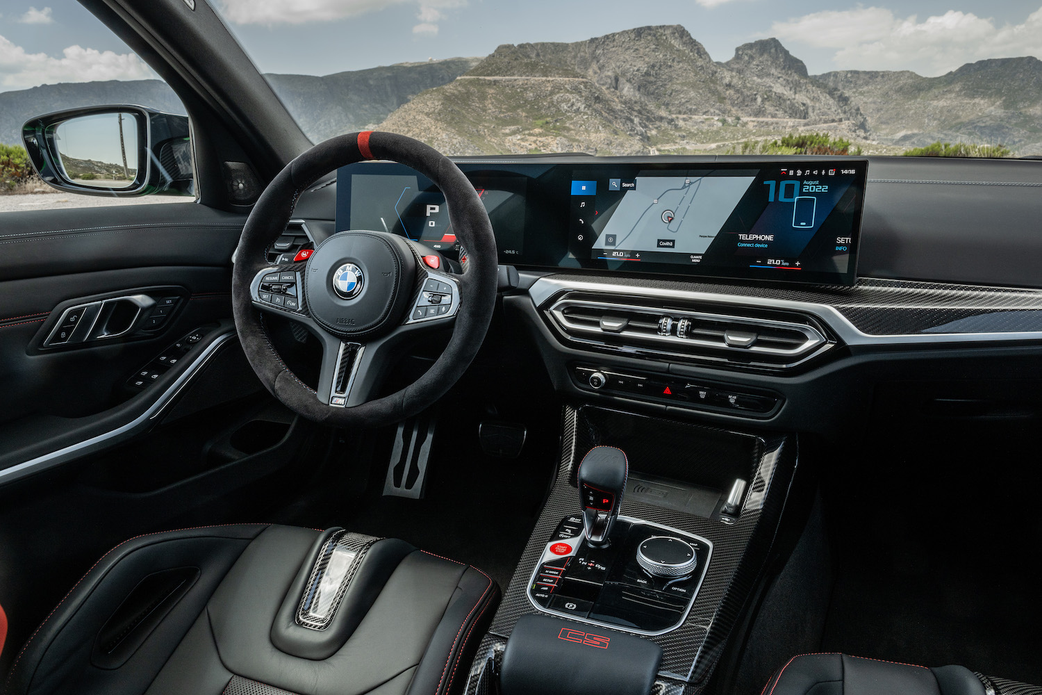2024 BMW M3 CS close up of steering wheel and dashboard with mountains in the back.