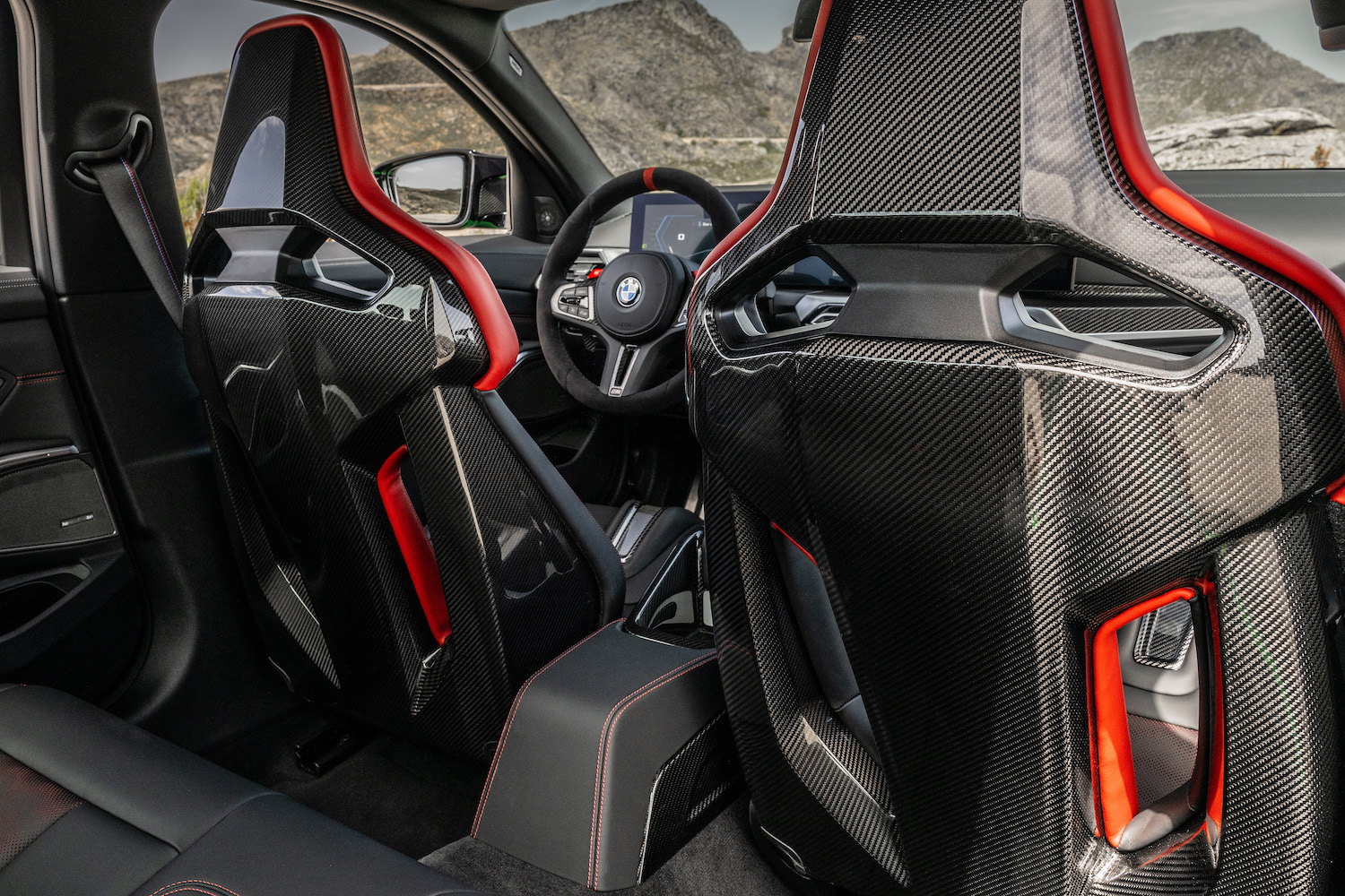 Back of 2024 BMW M3 CS bucket seats from rear passenger seat with mountains in the back.